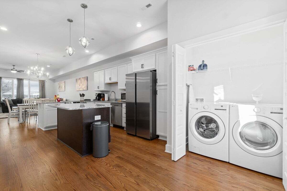 A modern kitchen with white cabinets, stainless steel appliances, and a central island.