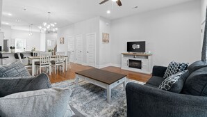 A spacious living room with a modern fireplace, a dining area with a white table and chairs, and a ceiling fan. - Unit #C 527 N 1st St (Clarksville)