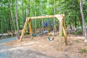A wooden swing set in a forested area.