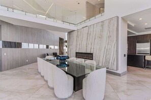A modern dining area with a glass-top table, white chairs, and a marble wall. - Villa Infinity by Rove Travel Pent W/seaview (Miami)