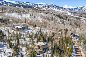 A modern lodge with a large central building, surrounded by snow-covered trees and mountains in the background.