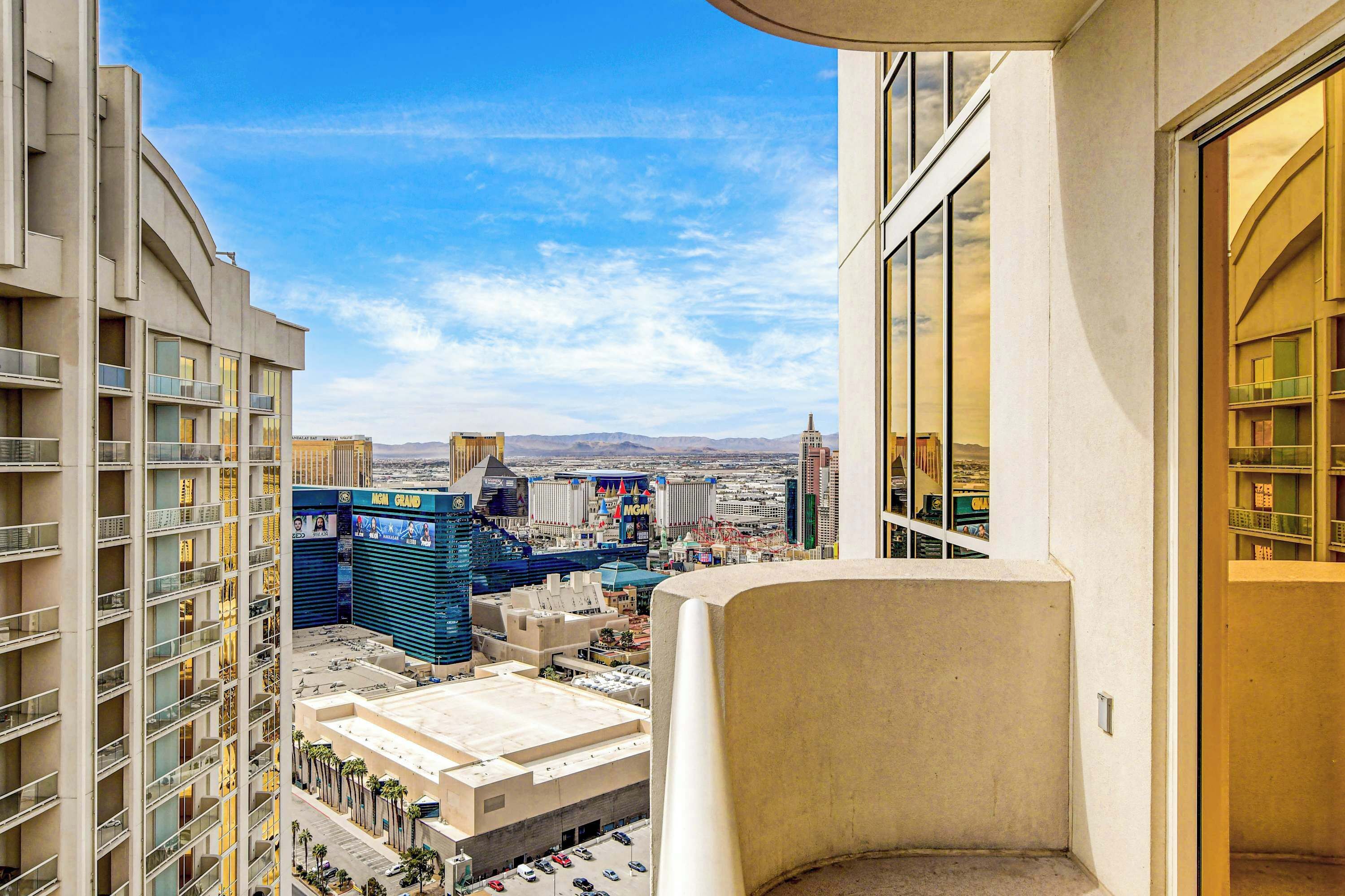 A high-rise hotel room with a view of the cityscape, including a casino and mountains in the distance.