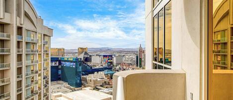 A high-rise hotel room with a view of the cityscape, including a casino and mountains in the distance.