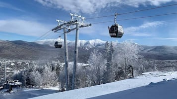 A ski lift system with cabins and chairs, set against a snowy mountain backdrop.