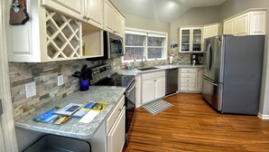 Una cocina moderna con armarios blancos, un refrigerador de acero inoxidable y una encimera de granito.