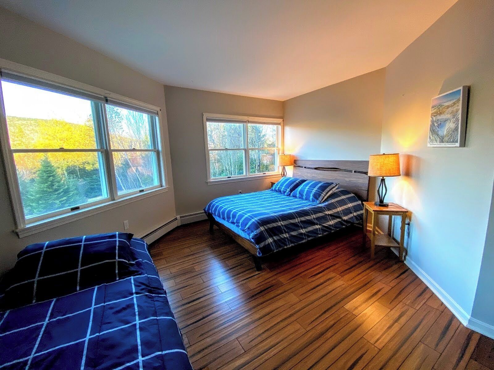 Une chambre avec deux lits, un plancher en bois et de grandes fenêtres.
