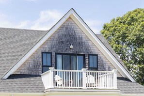 A house with a gabled roof, a balcony with white railings, and a window with a black frame. - Sandpoint by Rove Travel 6BR Family Home w Pool (Shelter Island)