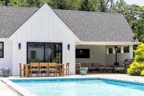 A modern house with a pool, a covered patio, and outdoor furniture. - Sandpoint by Rove Travel 6BR Family Home w Pool (Shelter Island)