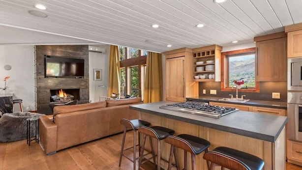 A modern kitchen with a large island, wooden cabinets, and a built-in fireplace. - Snowline Lodge 4BR Home With Hot Tub, Pool & BBQ (Aspen)