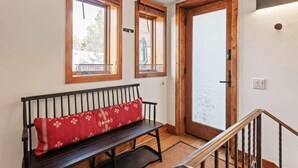 A hallway with a wooden bench, two windows, and a door. - Snowline Lodge 4BR Home With Hot Tub, Pool & BBQ (Aspen)