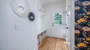 Ein Korridor mit einer weißen Tür, einer weißen Wand mit zwei runden Wandverzierungen und einem Holzboden.