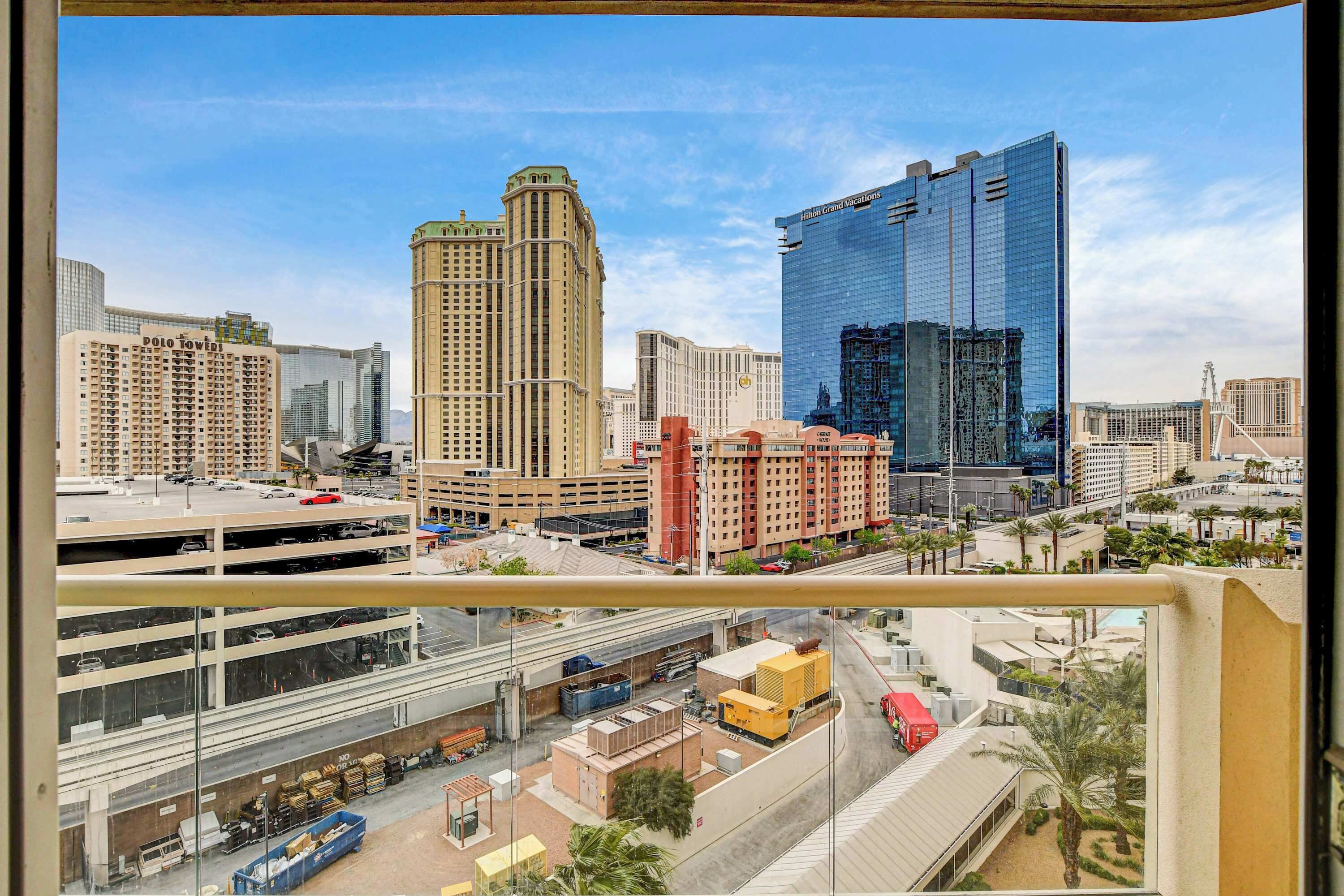 A cityscape with high-rise buildings, a parking garage, and a clear sky.