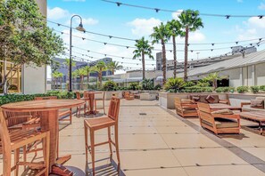 An outdoor patio area with wooden furniture, palm trees, and a clear sky. - Stunning Strip View Penthouse, Balcony 37617 (Las Vegas)