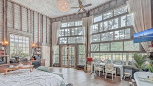 A spacious room with large windows, a bed, a desk, and a television. - The Charleston Treehouse (Wadmalaw Island)