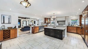 A spacious kitchen with a large island, dark cabinetry, and a ceiling fan. - Villa Justina by Rove Villa W/pool & Hot Tub (Miami)