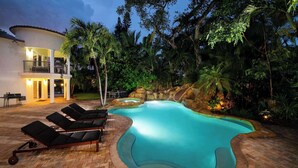 A swimming pool with lounge chairs, a hot tub, and a stone waterfall feature. - Villa Justina by Rove Villa W/pool & Hot Tub (Miami)