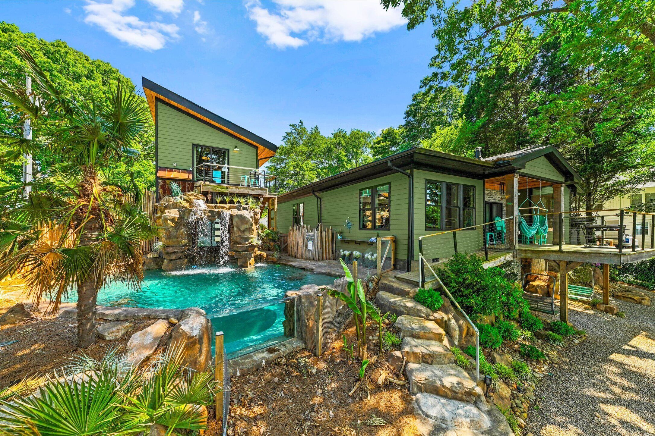 A house with a swimming pool, a waterfall, and a deck.