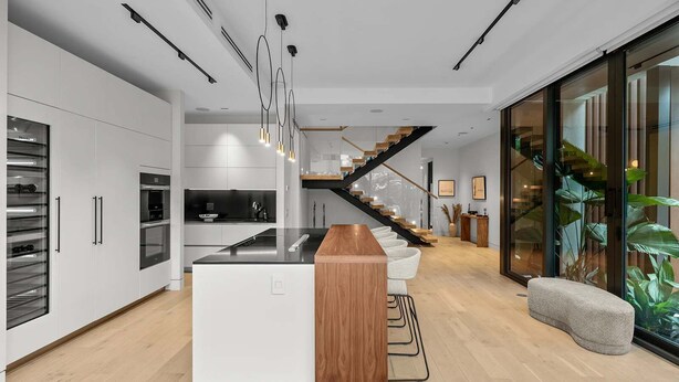 A modern kitchen with a central island, built-in appliances, and a staircase leading to an upper level. - Villa Ocean by Rove Travel Coastal Luxury Villa (Fort Lauderdale)