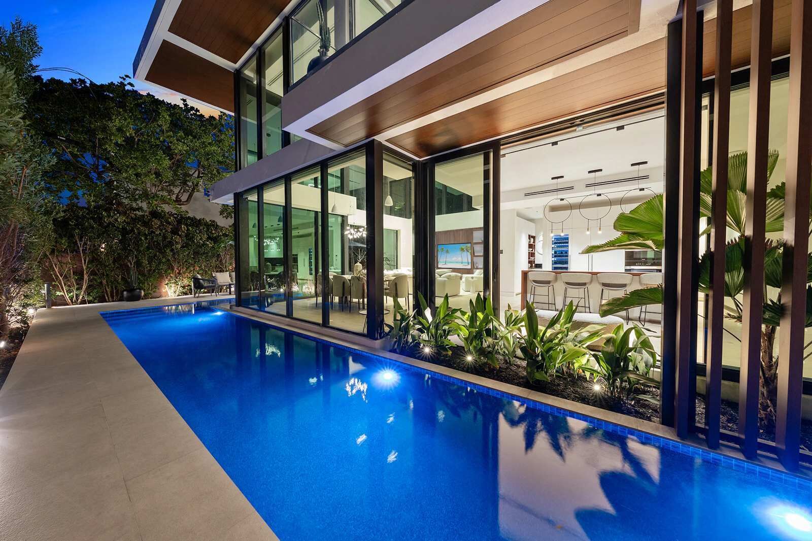 A modern house with a swimming pool, large windows, and indoor seating areas.