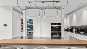 A modern kitchen with a central island, white cabinetry, and pendant lighting. - Villa Ocean by Rove Travel Coastal Luxury Villa (Fort Lauderdale)