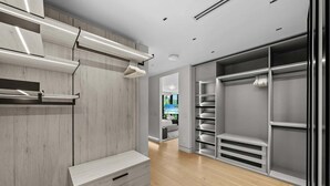 A modern walk-in closet with wooden paneling, built-in drawers, and a mirrored closet door. - Villa Ocean by Rove Travel Coastal Luxury Villa (Fort Lauderdale)