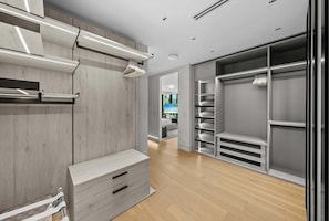 A modern walk-in closet with wooden paneling, built-in drawers, and a mirrored closet door. - Villa Ocean by Rove Travel Coastal Luxury Villa (Fort Lauderdale)