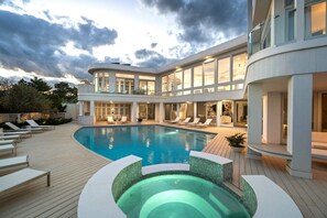 A modern hotel with a large pool, multiple balconies, and a well-lit interior.