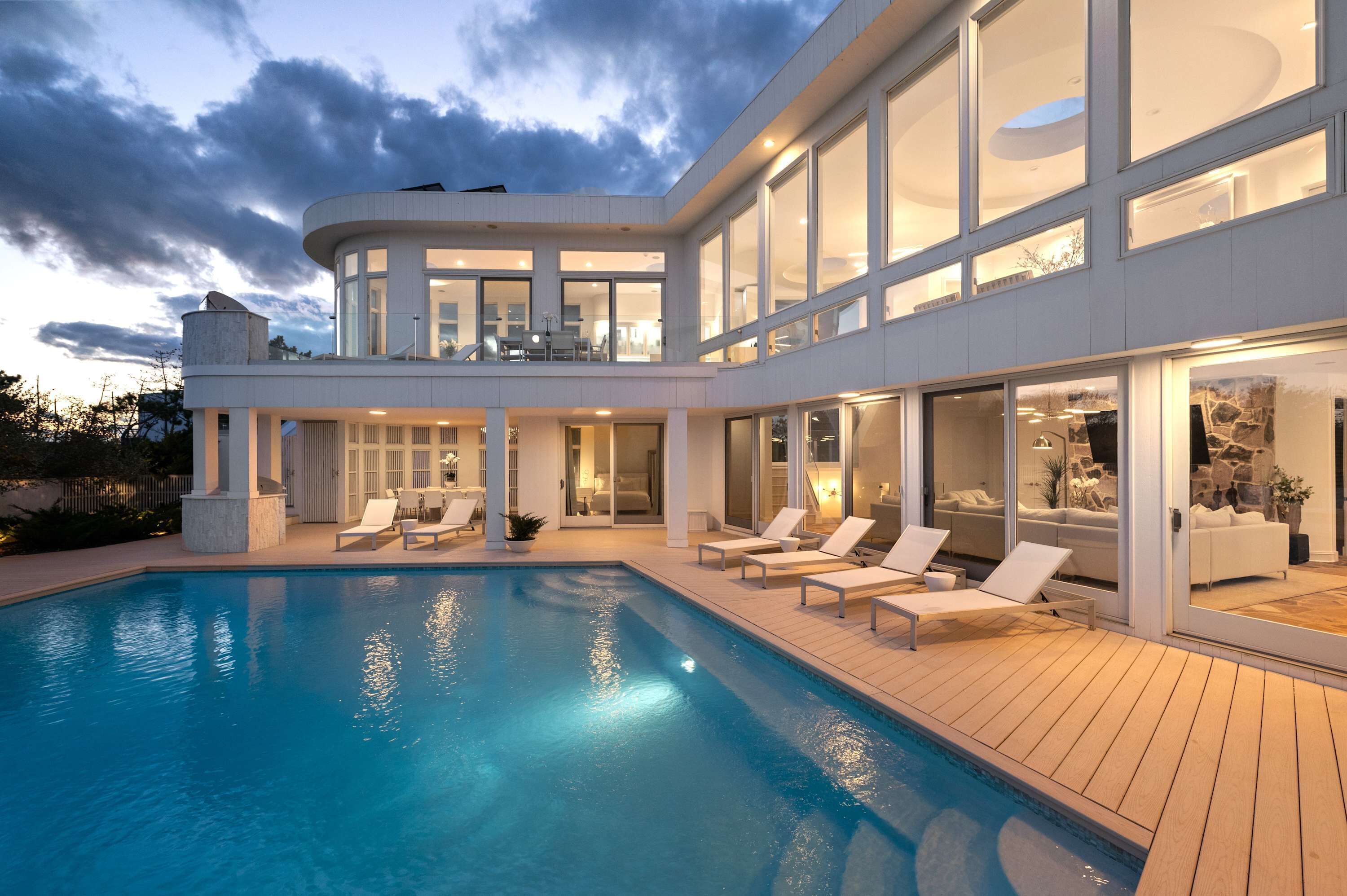 Et moderne hus med swimmingpool, liggestole og udsigt over det omkringliggende landskab.