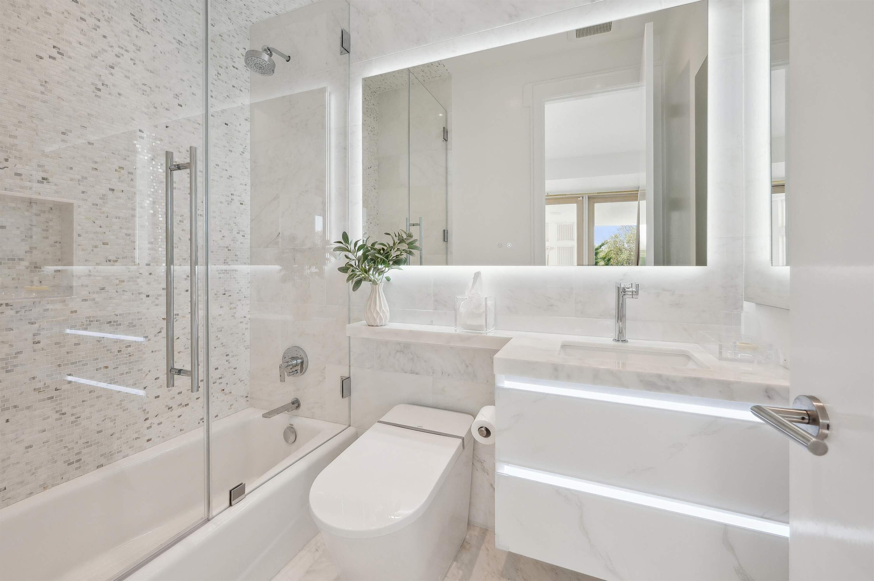 A modern bathroom with a glass-enclosed shower, a toilet, and a vanity with a mirror.