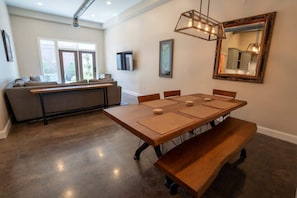 A dining area with a long wooden table, benches, and a hanging light fixture. - Downtown Urban Retreat 6 Beds Perfect for Groups (Roanoke)
