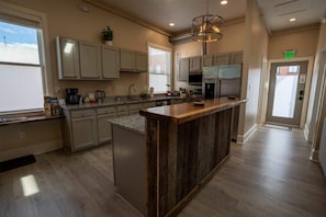 A modern kitchen with a central island, built-in appliances, and a large window providing natural light. - Downtown Urban Retreat 6 Beds Perfect for Groups (Roanoke)