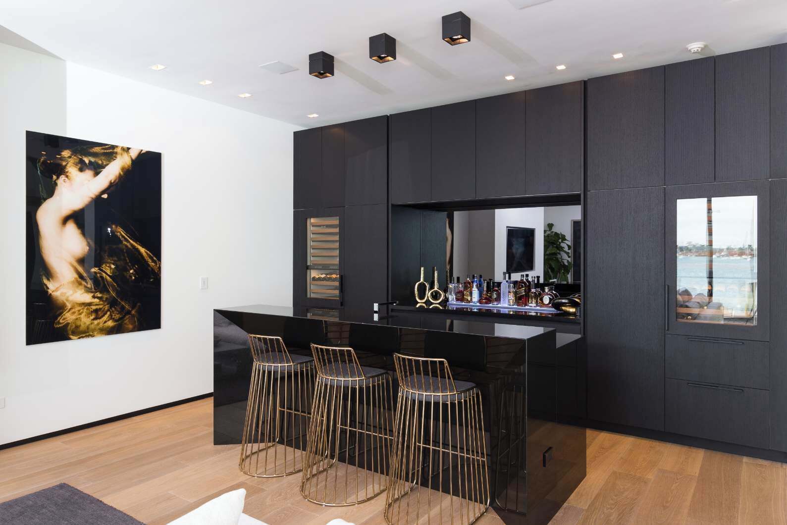 A modern kitchen with dark cabinetry, a central island with bar stools, and a large window with a view.