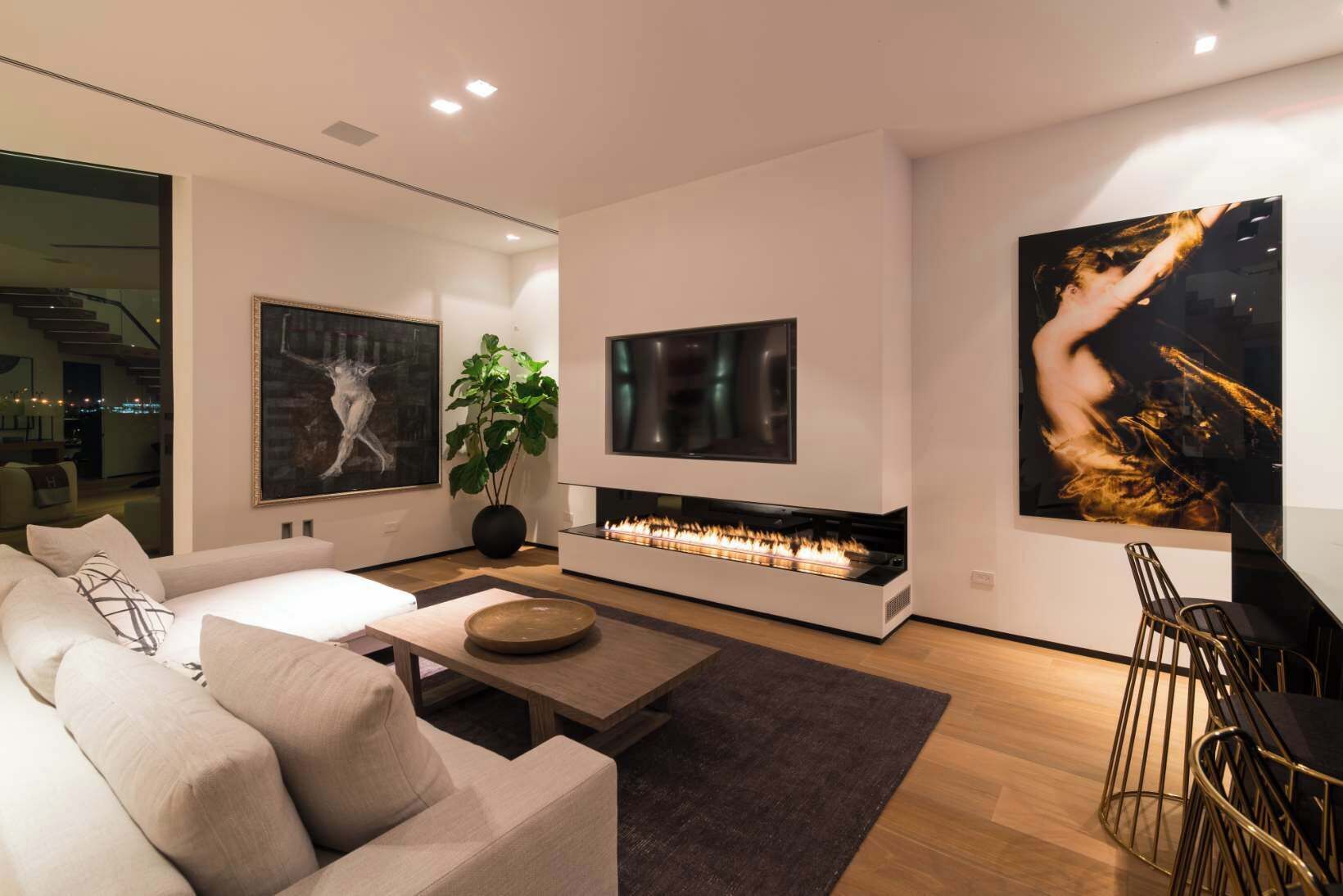 A modern living room with a sofa, a coffee table, a fireplace, and artwork on the walls.