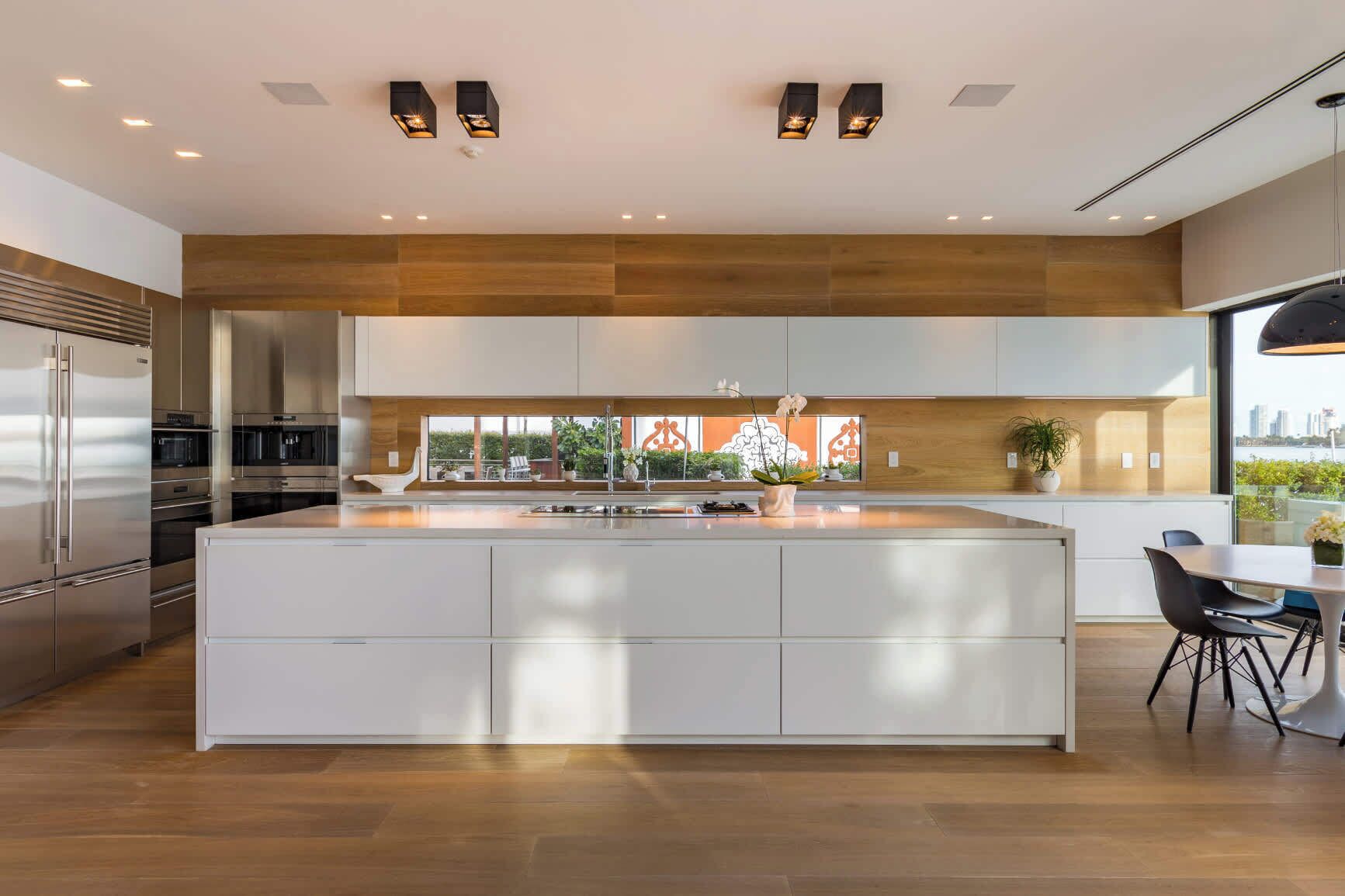 A modern kitchen with a large island, stainless steel appliances, and a view of the city.