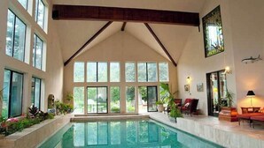 A large indoor swimming pool with a high ceiling and large windows. - Luxurious Mountain Retreat With Pool (Midway)