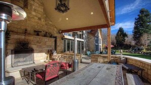 An outdoor patio with stone walls, a fireplace, and outdoor furniture. - Luxurious Mountain Retreat With Pool (Midway)