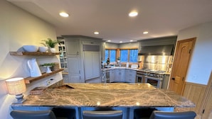 A kitchen with a granite island, bar stools, and a view of the outdoors. - CR1 Bretton Woods (Bretton Woods)