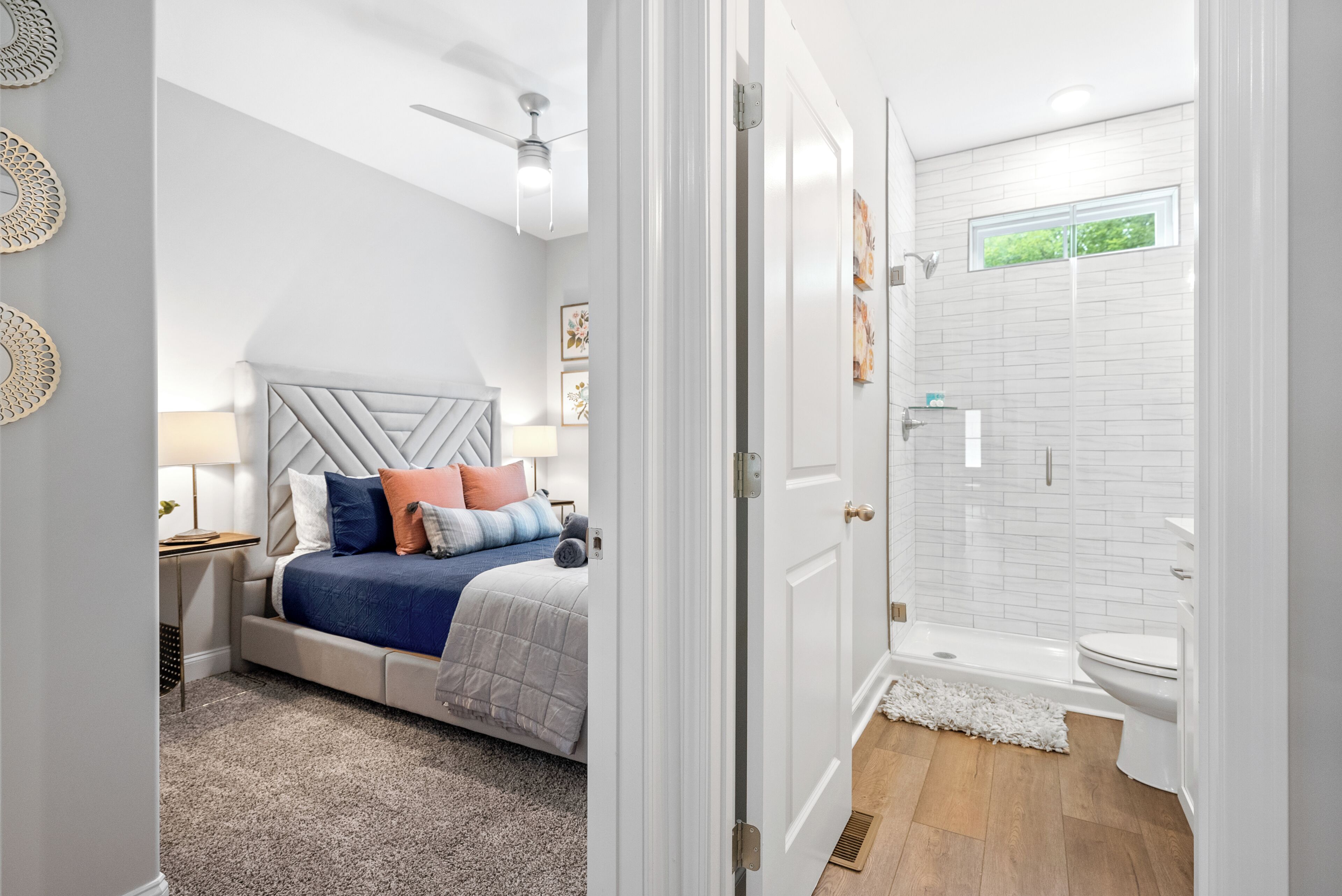 A bedroom with a bed, nightstand, and a ceiling fan. The bathroom has a shower, toilet, and a window.