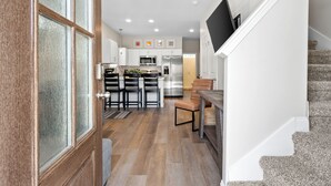 A modern kitchen with white cabinets, stainless steel appliances, and a dining area with a wooden table and chairs. - Whole Home 1012 & 1014 Franklin (Clarksville)