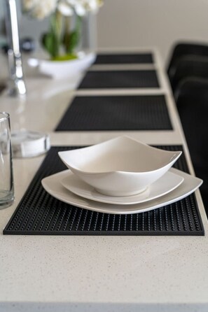 Una mesa de comedor con un plato blanco y un vaso de agua.