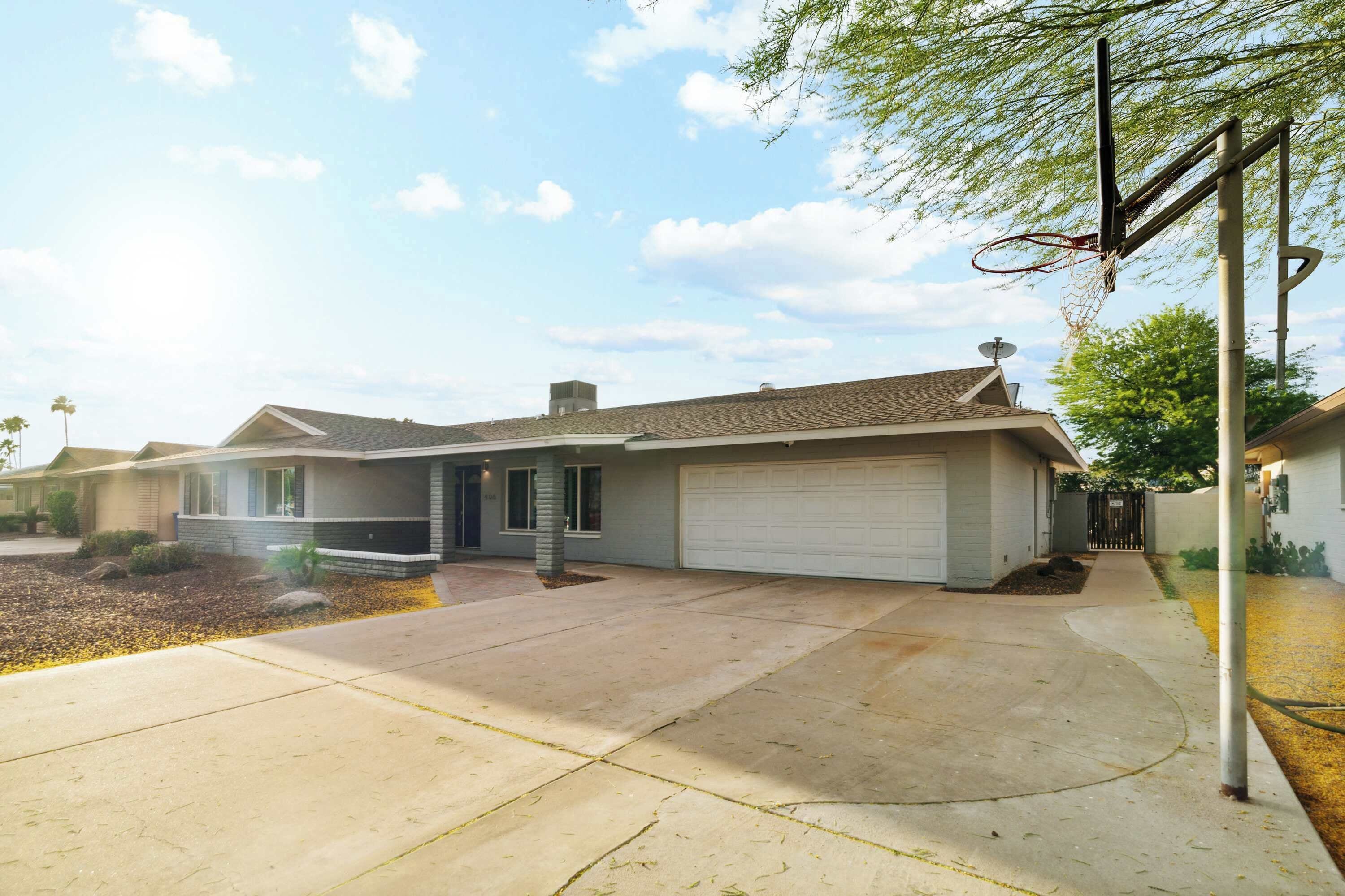 Una casa residencial con garaje, entrada para vehículos y un aro de baloncesto.