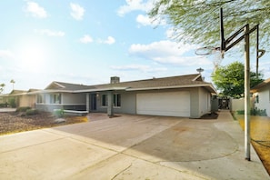 Una casa residencial con garaje, entrada para vehículos y un aro de baloncesto.