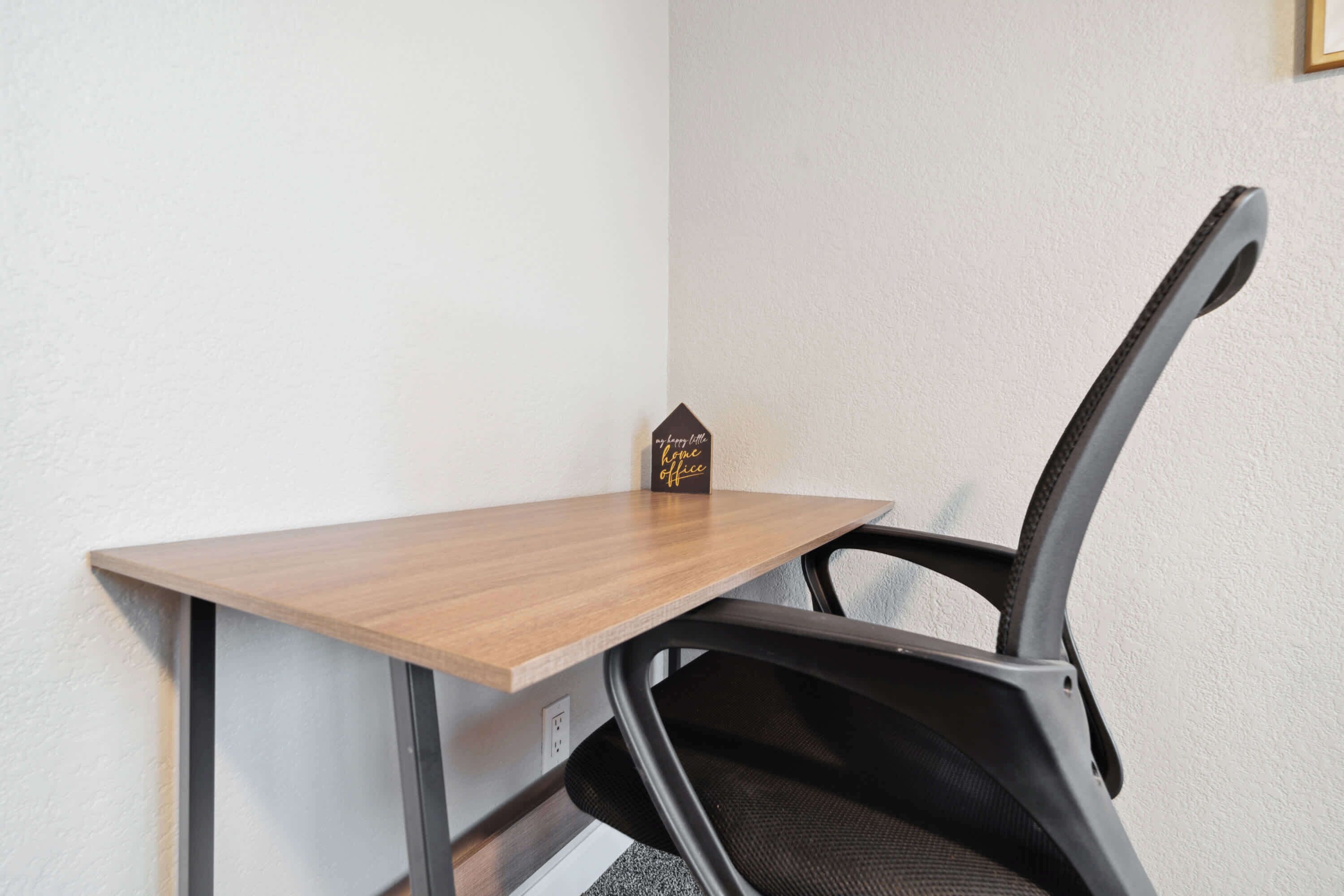 Un bureau d’angle avec une chaise, un petit objet décoratif et une prise de courant.