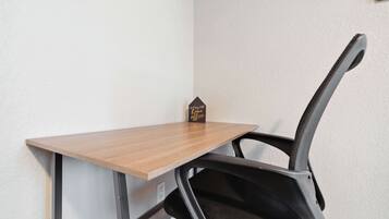Un bureau d’angle avec une chaise, un petit objet décoratif et une prise de courant.