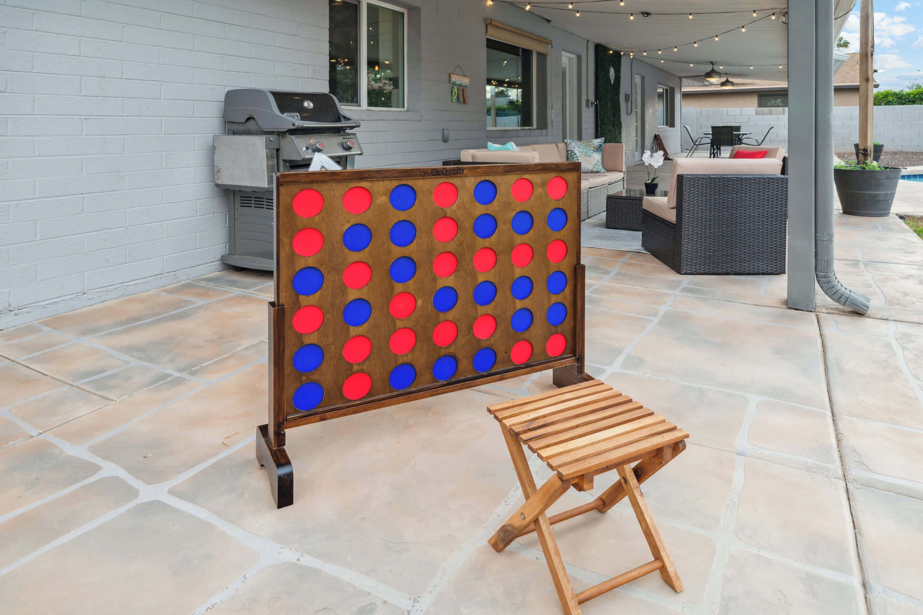 Un patio con un gioco da tavolo, una griglia, mobili da esterno e una pianta in vaso.