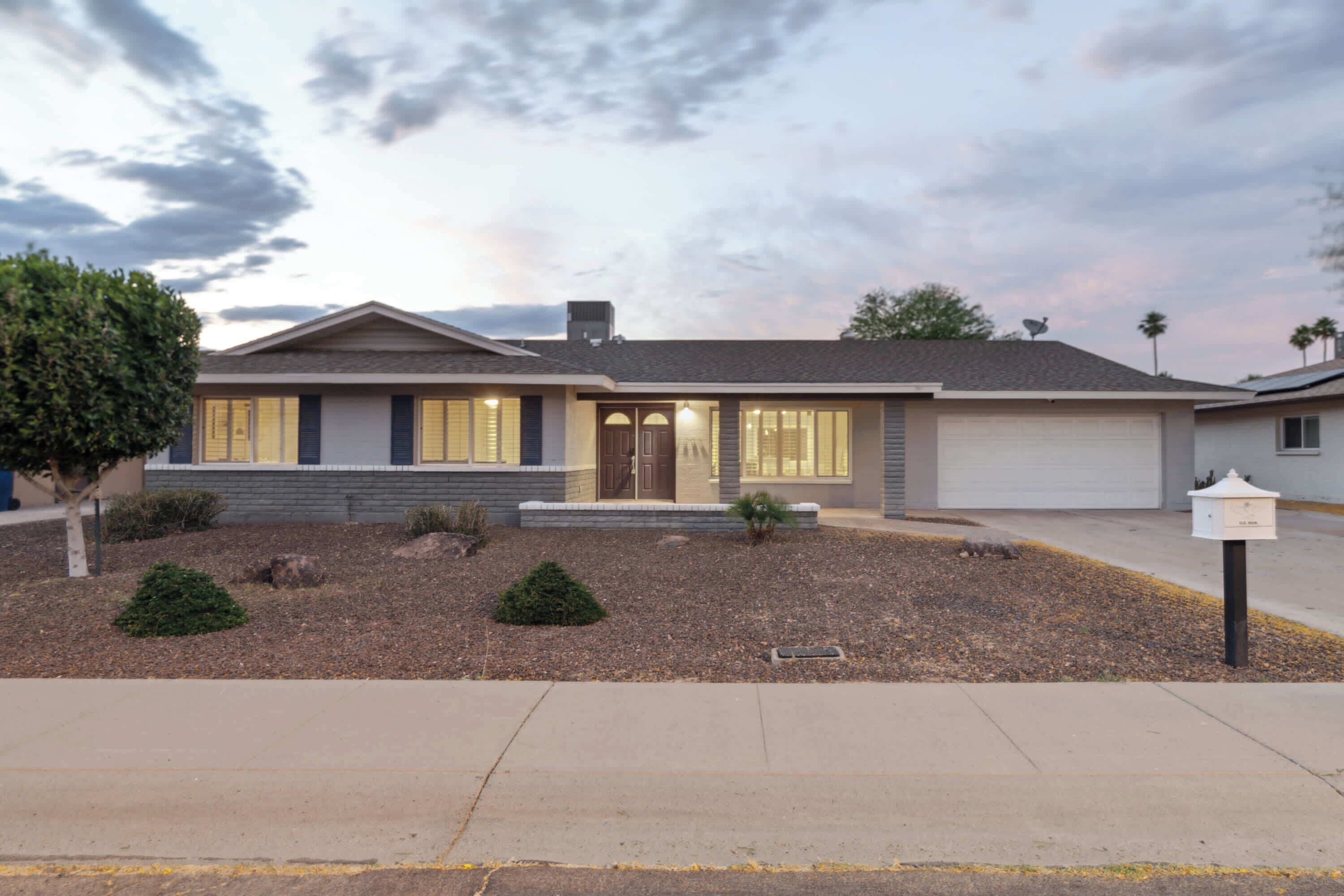 A two-story house with a front porch, a garage, and a landscaped front yard.