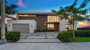 Una moderna casa a due piani con garage, ampie finestre e un cortile anteriore curato.
