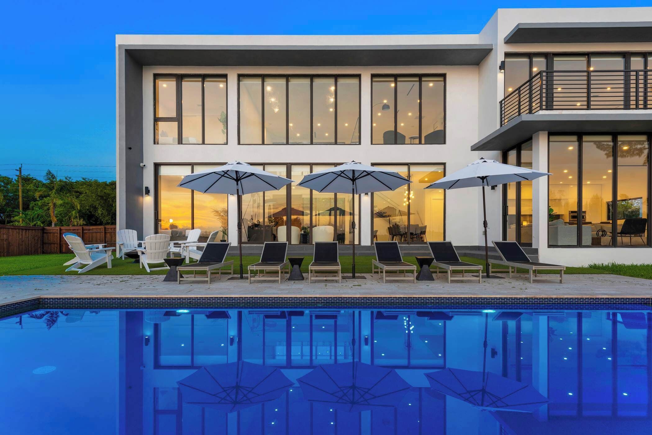 Uma casa moderna de dois andares com piscina, área de estar externa e janelas amplas.