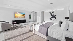 Una camera da letto moderna con un letto grande, una TV a schermo piatto e un arredamento minimalista.