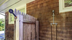 A wooden gate with a picket design, a metal gate latch, and a metal pipe attached to the wall. - Driftwood Cottage by Rovetravel 3BR Quiet Cottage (East Hampton)